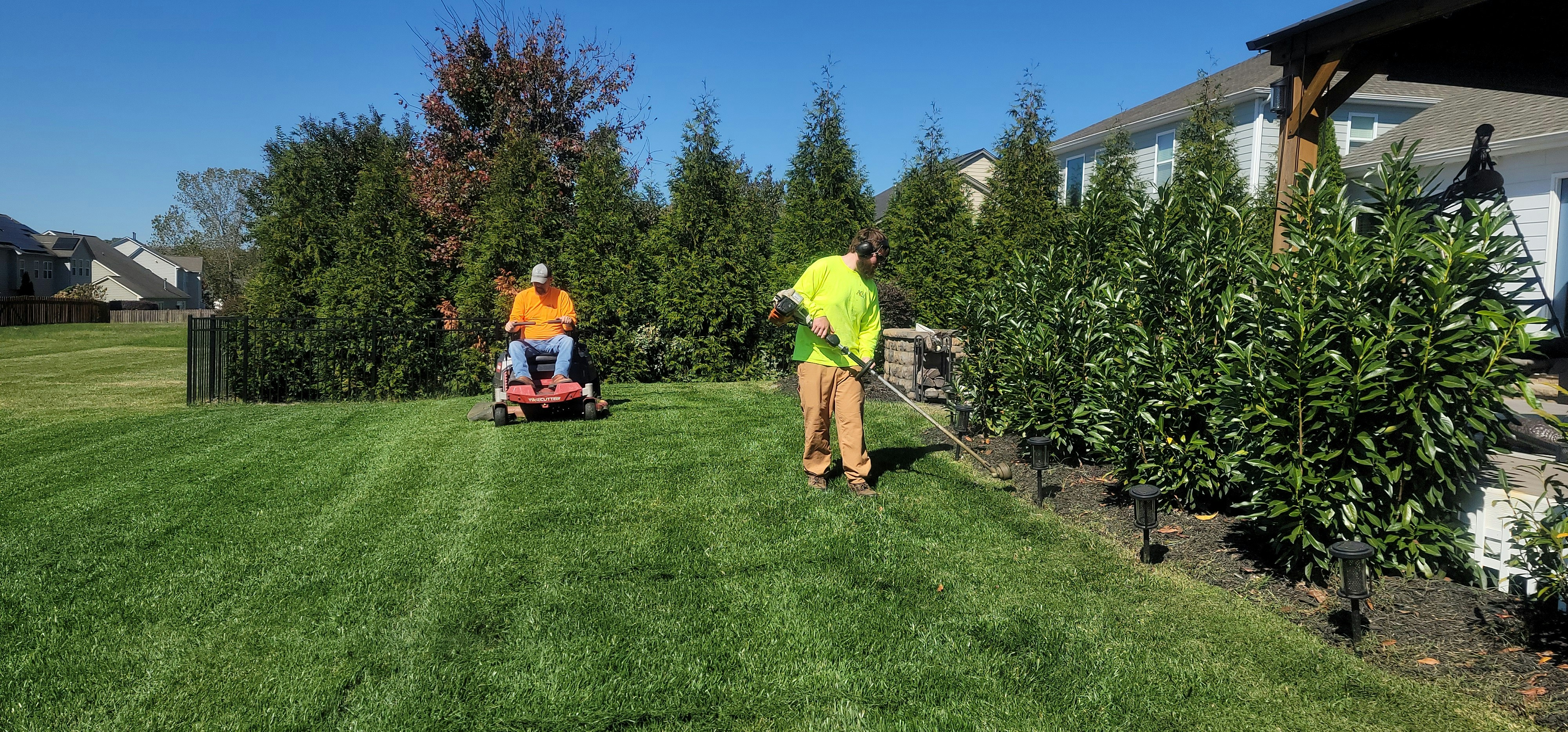 ProLand crew mowing and trimming a residential lawn