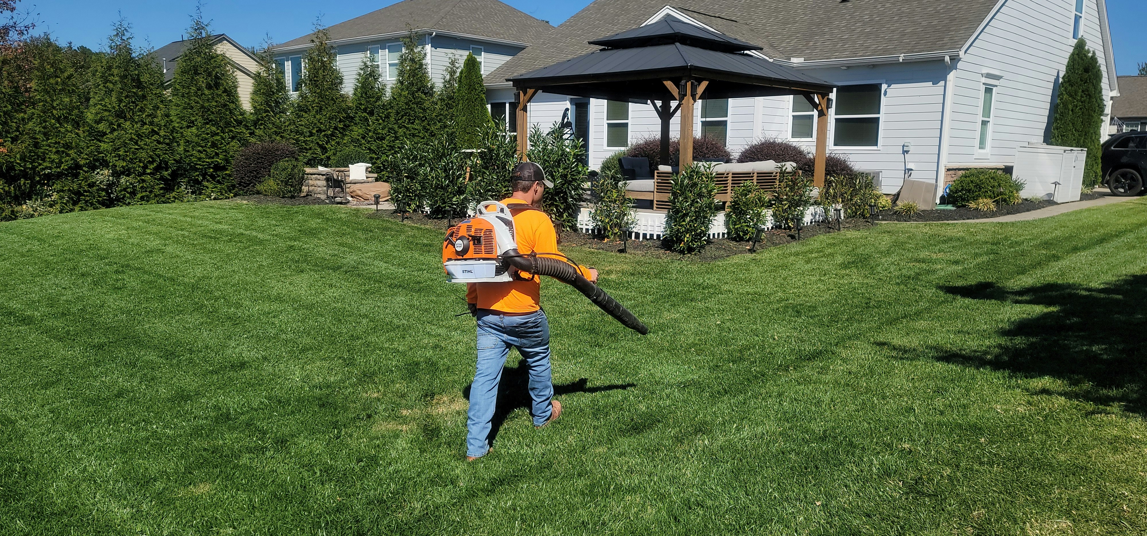 Lawn care professional with backpack blower on manicured lawn